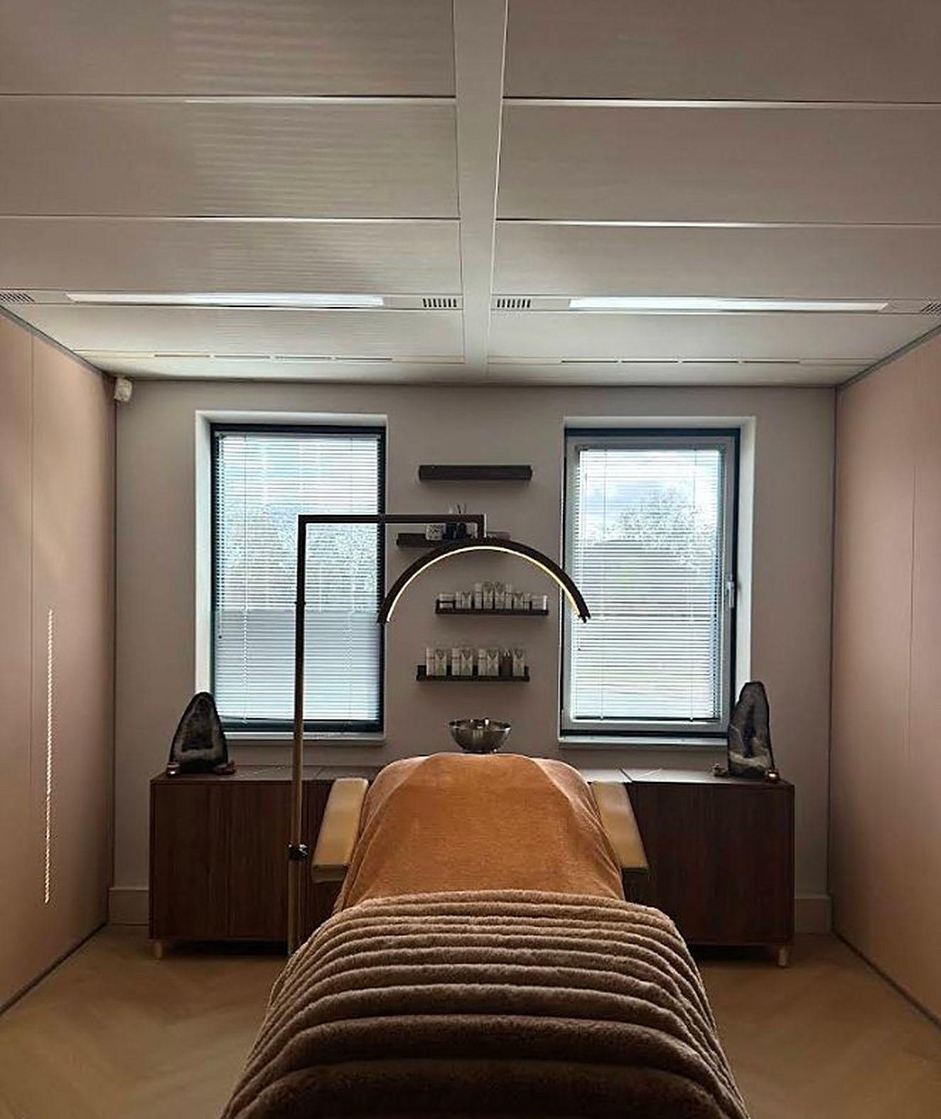 De behandelkamer met twee ramen, boogspiegel en behandelbed met bruine deken